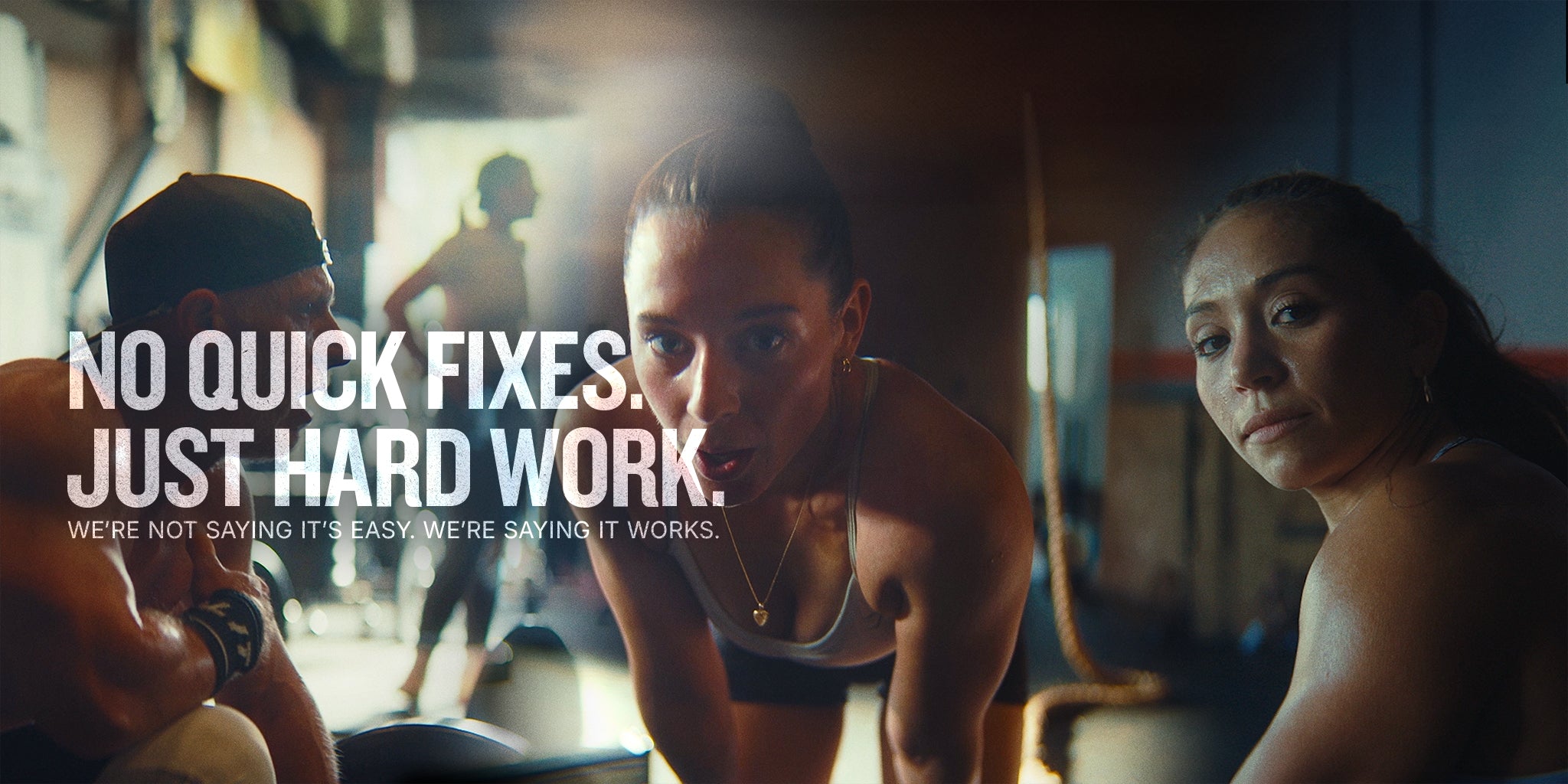 Three women in a gym setting with motivational text overlay.